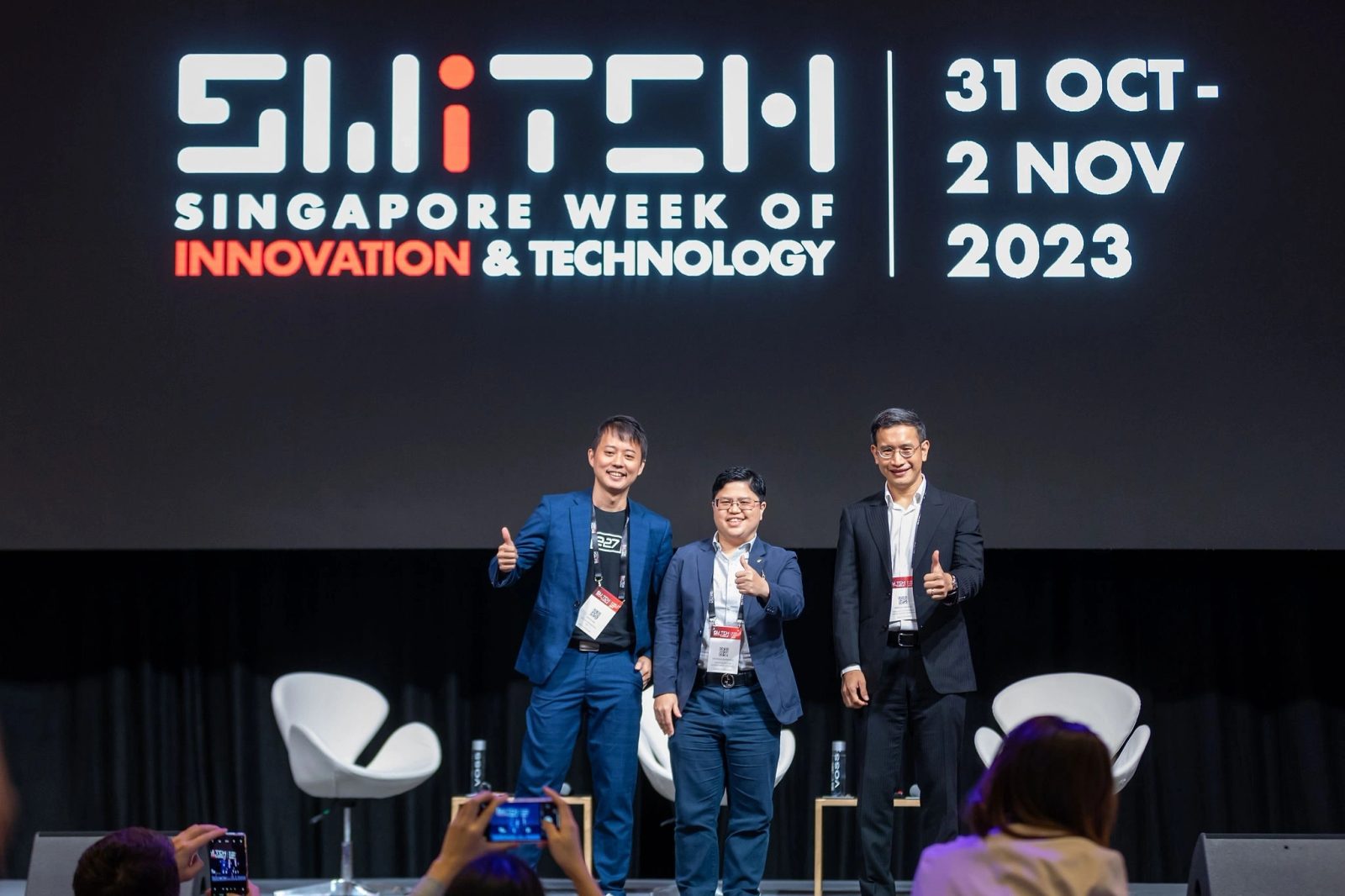 Speakers posing on stage after a session at a Singapore innovation conference