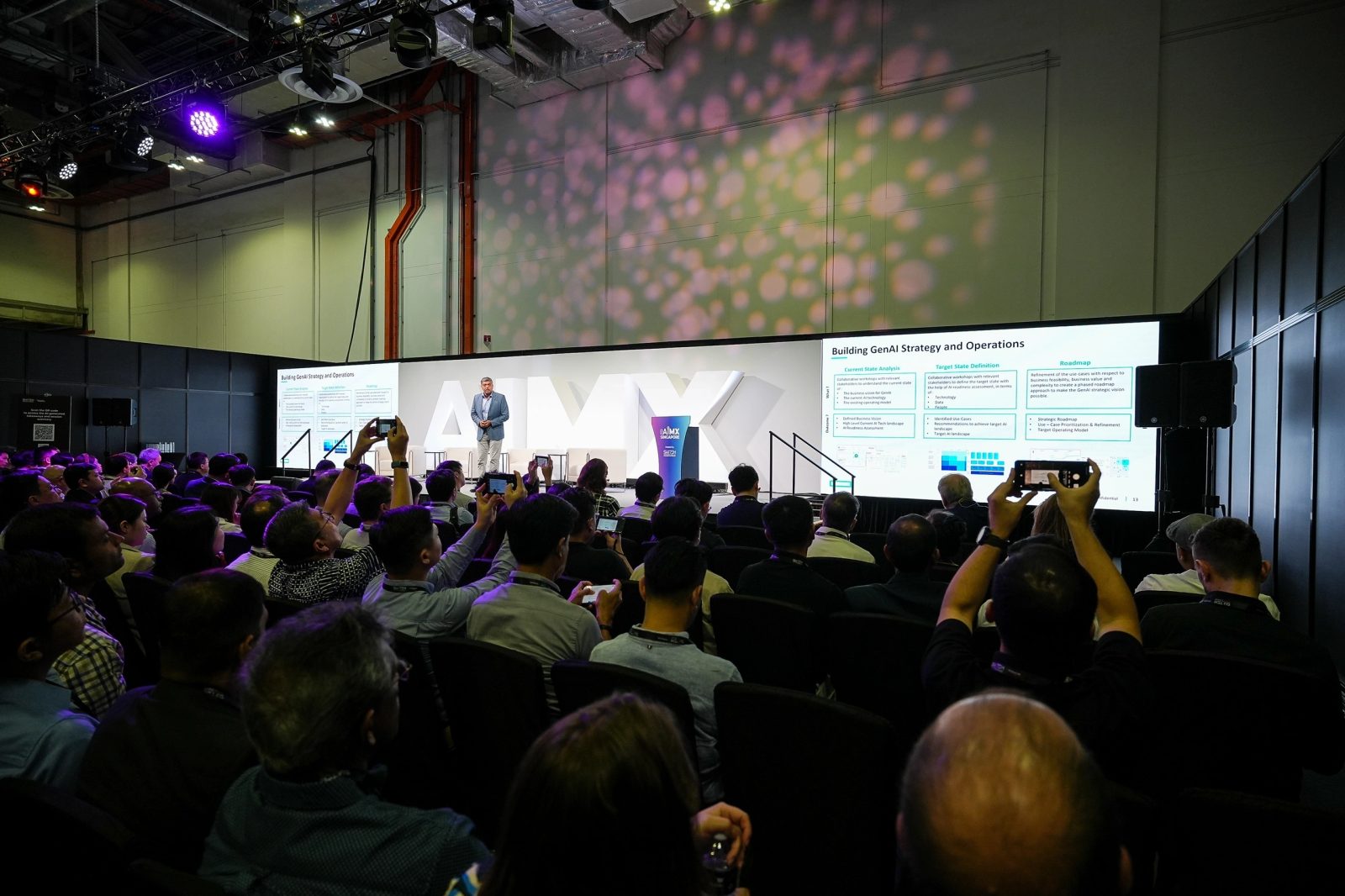 Conference audience watching a presentation across two large LED screens